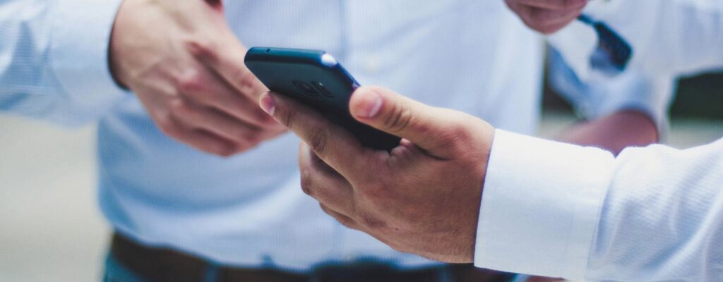 Office workers reviewing mobile device management on a cell phone
